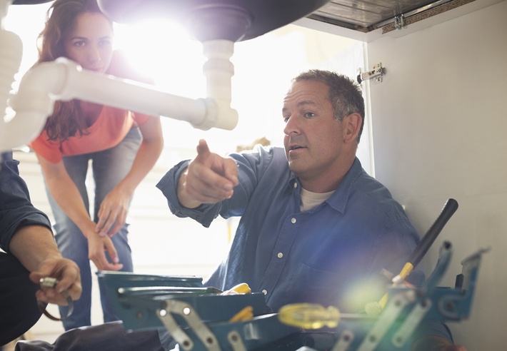 plumber showing homeowner a problem with plumbing