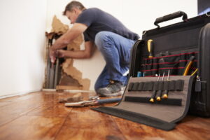 Middle aged man repairing burst pipe,plumbing, focus on foreground